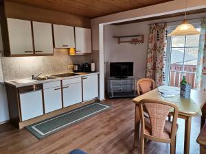 a kitchen with white cabinets and a table with a tableablish at Aparthotel Landhaus Schwaighofer in Russbach am Pass Gschütt