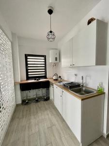 a kitchen with white cabinets and a sink and a window at Dany Studio in Eforie Nord +5 photos