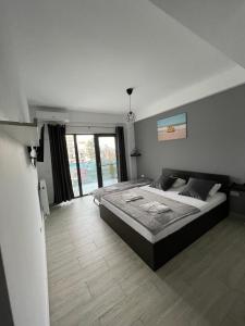 a bedroom with a large bed and a large window at Dany Studio in Eforie Nord