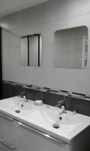 a white bathroom with two sinks and a mirror at appartement au rez de jardin in Morangis