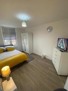 een slaapkamer met een geel bed en een televisie bij 2 bedroom apartment in Londen