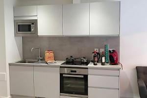a kitchen with white cabinets and a stove top oven at Snuggle Flat in Sheffield in Sheffield