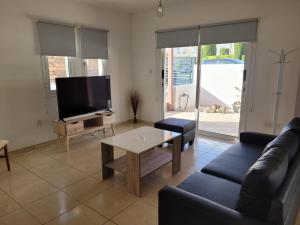 a living room with a couch and a tv and a table at ELeAN VILLA in Paphos City