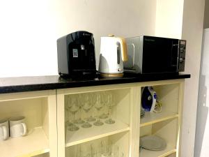 a microwave and coffee maker on a shelf with wine glasses at Affordable Long Stay Private Rooms A Few Minutes From The City - Wolverhampton in Wolverhampton