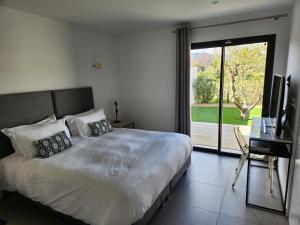 sypialnia z dużym łóżkiem i przesuwnymi szklanymi drzwiami w obiekcie Villa HOME HOLIDAY à Cala Rossa w mieście Lecci
