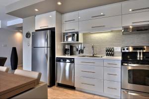uma cozinha com armários brancos e um frigorífico de aço inoxidável em Les Immeubles Charlevoix - Le 1172 em Cidade de Quebec