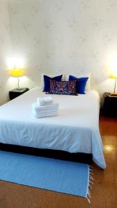 a bedroom with a white bed with blue pillows at Soleil Bleu in Vila Nova de Milfontes