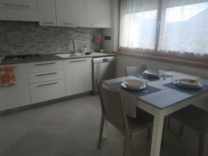 eine Küche mit einem Tisch, Stühlen und einem Waschbecken in der Unterkunft A due passi dalla ciclabile in Calalzo