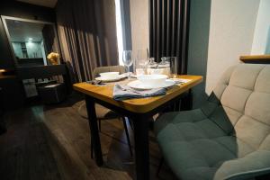 a wooden table with glasses and plates and a chair at Tokhtarov Apartment in Ustʼ-Kamenogorsk