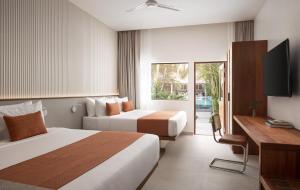 a hotel room with two beds and a television at Plantation Urban Resort & Spa in Phnom Penh