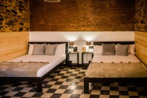 two beds in a room with a checkered floor at Hotel Casa Luna in Zafra