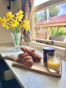 einen Tisch mit Brot und ein Glas Orangensaft und Blumen in der Unterkunft Alice’s Garden @ Bleak House Farm in York