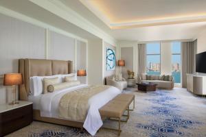 a bedroom with a large bed and a living room at The St. Regis Doha in Doha