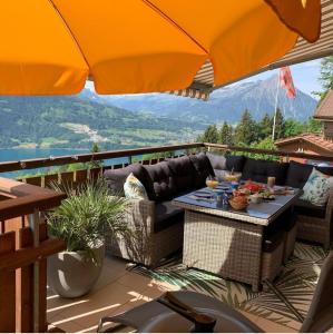 une terrasse avec une table, des chaises et un parasol dans l'établissement Königin der Alpen, à Beatenberg