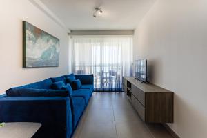 un soggiorno con divano blu e TV di Gospa 58 - 2 bedroom apt a Birżebbuġa