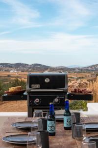 a table with two bottles of wine and a grill at Ventu Paros Villa - Pet Friendly in Márpissa