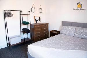 um quarto com uma cama, uma cómoda e um espelho em Spacious 3 bed Terrace House with free parking & free Wi-Fi by Amazing Spaces Relocations Ltd em Saint Helens