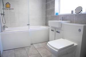 a white bathroom with a toilet and a sink at Spacious 3 bed Terrace House with free parking & free Wi-Fi by Amazing Spaces Relocations Ltd in Saint Helens