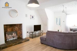 a living room with a couch and a fireplace at Spacious 3 bed Terrace House with free parking & free Wi-Fi by Amazing Spaces Relocations Ltd in Saint Helens