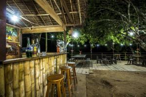 un bar con taburetes, mesas y sillas por la noche en Majacho`s House, en Puerto Maldonado
