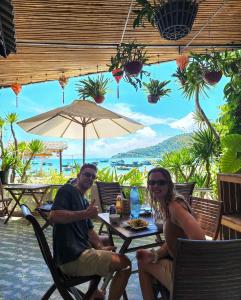 um homem e uma mulher sentados numa mesa com um guarda-chuva em Monkey Homestay & Bar em Tân Hiệp