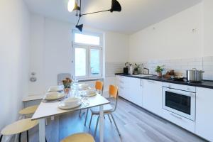 cocina blanca con mesa y sillas en vonBehling Boutique Apartment - Gemeinsam leben am Puls der Innenstadt en Wiesbaden