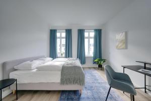 biała sypialnia z łóżkiem i biurkiem w obiekcie vonBehling Boutique Apartment - Gemeinsam leben am Puls der Innenstadt w mieście Wiesbaden