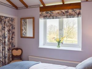 a bedroom with a window with a vase of flowers at Little Folly in  Liscombe