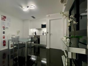 a white kitchen with a glass table and chairs at Sea and Sun 4 You - Jardins da Imperatriz in Funchal