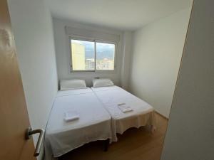 a small white room with a bed and a window at Atico en Port gran Roses in Roses