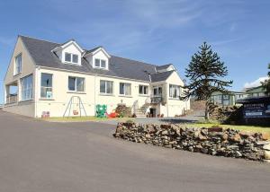 a large white house with a rock wall in front of it at Whitecairn Holiday Park in Glenluce