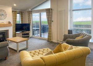a living room with a yellow couch and a television at Whitecairn Holiday Park in Glenluce