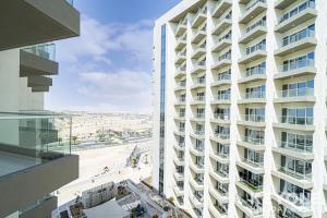 a tall white building with a view of a beach at Modish Studio in Damac Hills 2 in Dubai