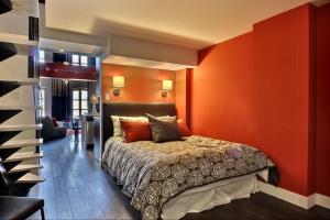 ein Schlafzimmer mit einem Bett in einer roten Wand in der Unterkunft Les Immeubles Charlevoix - Le 1180 in Québec