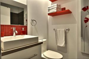 a white bathroom with a sink and a toilet at Les Immeubles Charlevoix - Le 1180 in Quebec City +6 photos