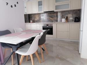 uma cozinha branca com uma mesa e cadeiras em Aqua West Apartment free parking- self check-in em Oradea