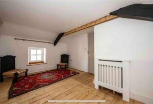 an empty living room with a red rug and a window at Quirky Cottage in the Heart of Appleby in Appleby