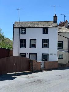 a white house with a fence in front of it at Quirky Cottage in the Heart of Appleby in Appleby