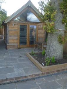 a wooden cabin with a tree next to a tree at Oak Frame Barn Studio in Rural AONB Chiddingfold in Chiddingfold