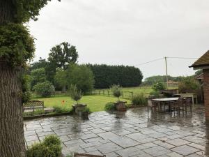a patio in the rain with a table and chairs at Oak Frame Barn Studio in Rural AONB Chiddingfold in Chiddingfold