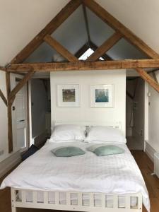 a bedroom with a white bed with two pillows at Oak Frame Barn Studio in Rural AONB Chiddingfold in Chiddingfold