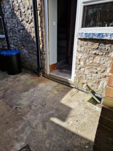 una puerta abierta de un edificio de ladrillo con un cubo de basura en Lovely Cosy Two Bed Home,Peak District Gateway, en Buxton