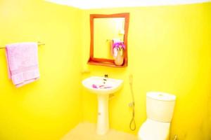 a yellow bathroom with a sink and a toilet at Talalla Freedom Resort in Talalla