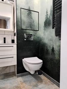 a bathroom with a toilet and a painting of trees at Apartament Lipova in Piechowice