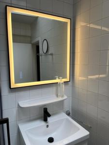 bagno con lavandino bianco e specchio di Appartement Wim a Blankenberge