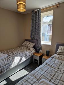 1 dormitorio con 2 camas y ventana en Lovely Cosy Two Bed Home,Peak District Gateway, en Buxton