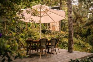a table and chairs with an umbrella on a deck at AMAYA HOME - Lodge, Spa & Restaurant Sóc Sơn in Sóc Sơn