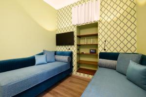 La Casa di Vittoria Sorrento في سورينتو: غرفة معيشة مع اثنين من الأرائك الزرقاء وتلفزيون