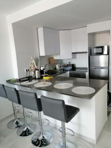 a kitchen with a counter with four bar stools at Casares Cozy Apartment in Casares