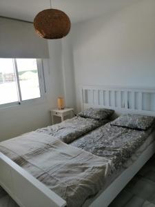 a white bedroom with a large bed and a window at Casares Cozy Apartment in Casares
